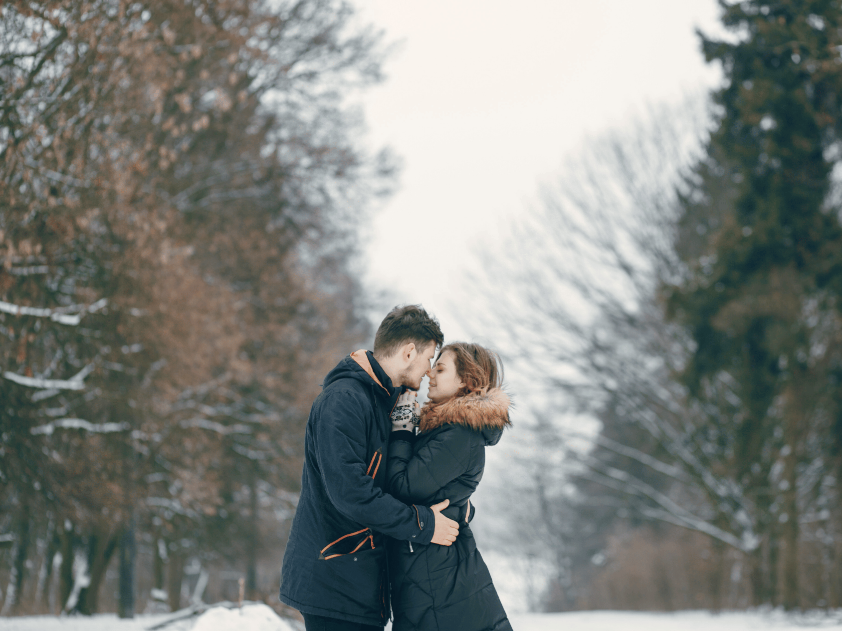 A couple embracing in a snowy woody mountain