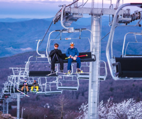 A ski lift filled with ski goers climbing the mountain 